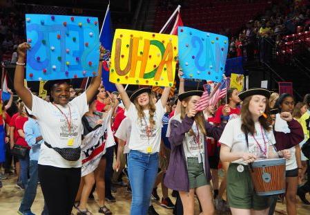 Students marching in the NHD Parade at the National Competition.  The students are wearing NHD Massachusetts T-shirts and wearing tricorn colonial caps.  Three students in the foreground carry signs that read 